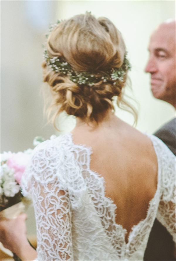 A Twisted Low Bun Wedding Hairstyle with Greenery and Flower Crown