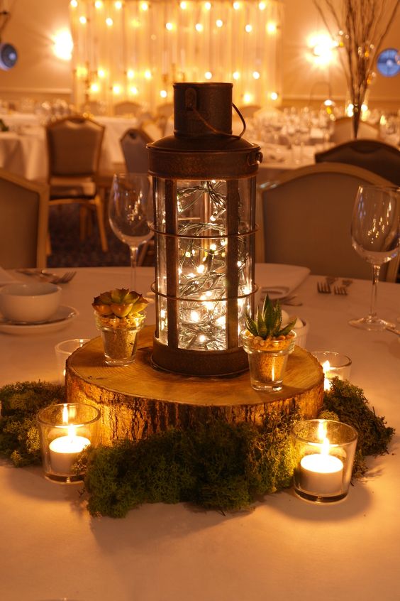 Woodland wedding themed table centres with moss, succulents, votives and a copper lantern with pealights by stressfreehire
