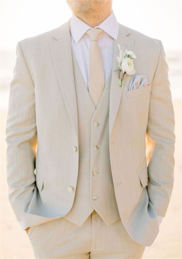 A groom wearing an ivory three-piece suit with a matching vest and tie