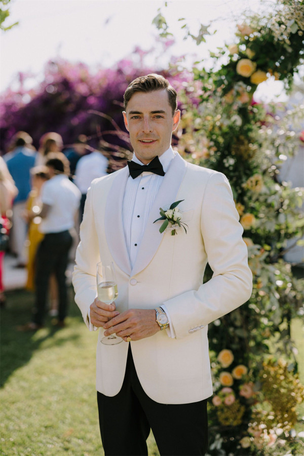 A groom in a vintage-inspired white suit with suspenders