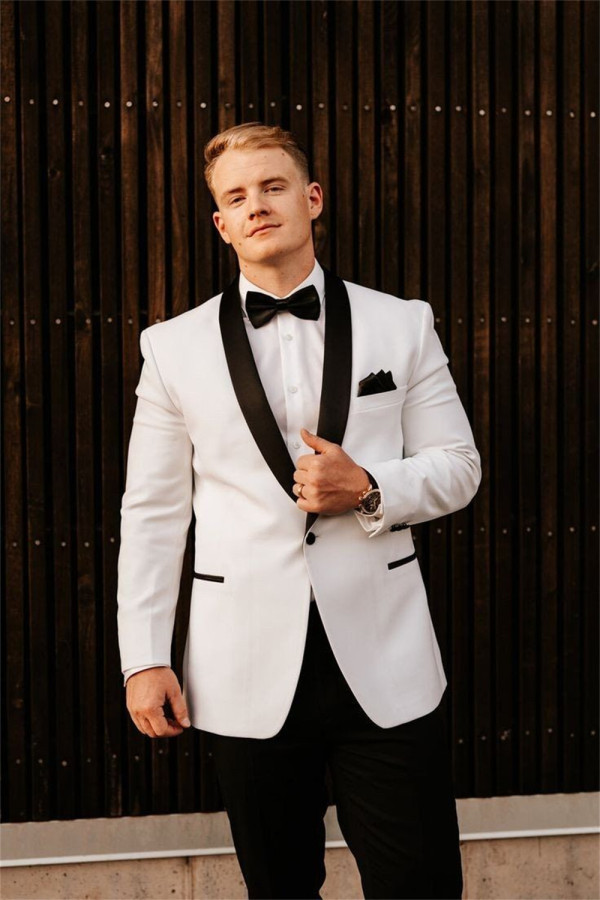 A groom in a white velvet tuxedo with a black bow-tie